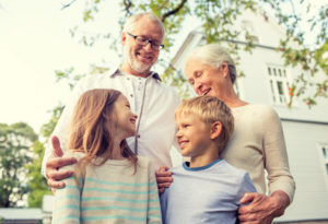 family, happiness, generation, home and people concept - happy family standing in front of house outdoors